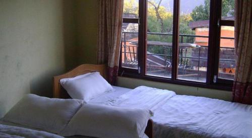 a bedroom with two beds and a window with a view at Mystique Highland Resort in Pokhara