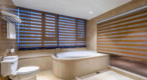 a bathroom with a tub and a toilet and a bath tub at Haikou Kai Wei Hotel in Haikou