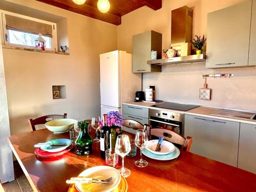a kitchen with a wooden table with plates and wine glasses at Poggelleri la cartolina su Poppi e le colline toscane in Poppi