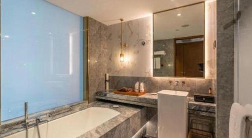 a bathroom with a tub and a sink and a mirror at Grand Metropark Hotel Chongqing in Chongqing