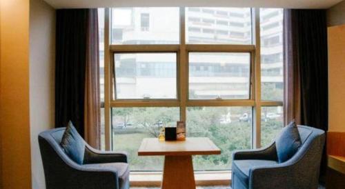 a room with two chairs and a table in front of a window at Grand Metropark Hotel Chongqing in Chongqing
