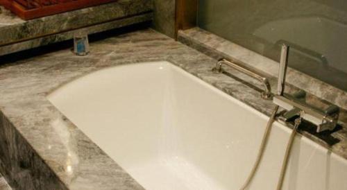 a white tub in a bathroom with a sink at Grand Metropark Hotel Chongqing in Chongqing