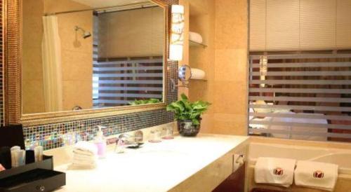a bathroom with a sink and a large mirror at Dunhuang Grand Soluxe Hotel in Dunhuang