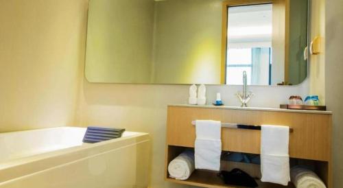 a bathroom with a tub and a sink and a mirror at Beluga Sanya Discovery Ocean World in Shangsimacun