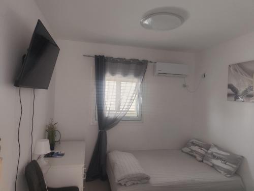a small bedroom with a bed and a window at Apartment with terrace and parking in Eilat