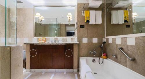 a bathroom with a tub and a sink and a mirror at Kai Wah Plaza International Hotel in Kunming