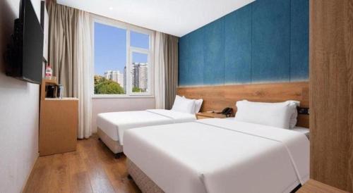 a hotel room with two beds and a television at New Beacon Sunyee SPA Hotel in Wuhan