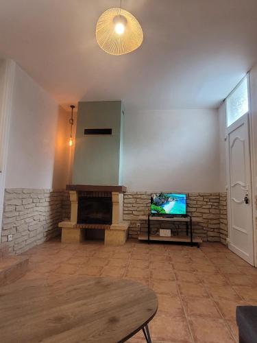 a living room with a fireplace and a tv at Charmante maison en bord de Vire à Saint-Fromond in Saint-Fromond