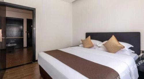 a bedroom with a large white bed with pillows at H Life Hotel Nanshan Branch in Shenzhen