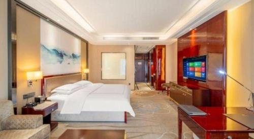 a bedroom with a large bed and a flat screen tv at Northwest Petroleum Hotel in Ürümqi