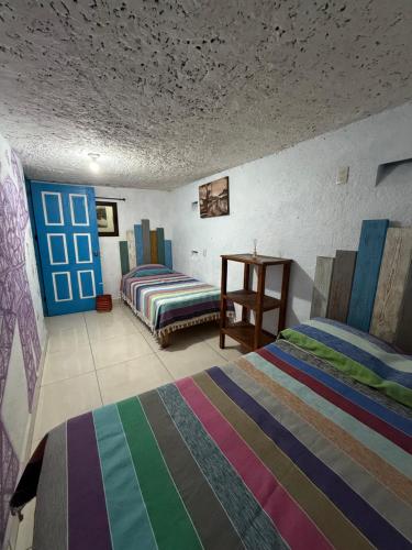 a room with two beds and a table in it at Hostal el Alebrije in Valle de Bravo