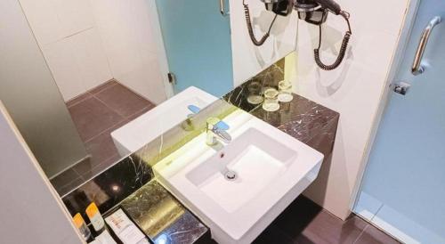 a bathroom with a white sink and a mirror at Brits Hotel Karawang in Karawang