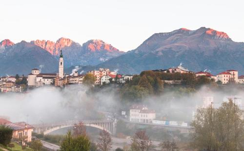 a city with a bridge and mountains in the background at Hotel Europa Belluno in Belluno