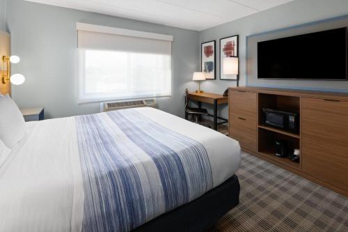 a hotel room with a bed and a flat screen tv at AmericInn by Wyndham Chippewa Falls in Chippewa Falls