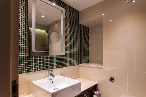 a bathroom with a sink and a mirror at 100 Queen's Gate Hotel London Kensington, Curio Collection by Hilton in London