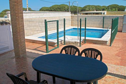 una mesa y sillas en un patio con piscina en Chalet Arroyo Majadales 107, en Conil de la Frontera