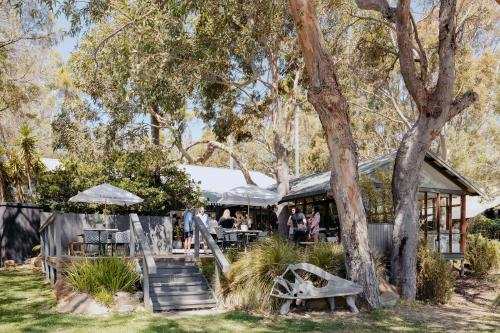 a restaurant with people sitting at tables under trees at Empire Spa Retreat in Dunsborough