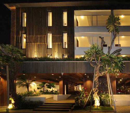 a building with palm trees in front of it at The Bene Hotel in Kuta