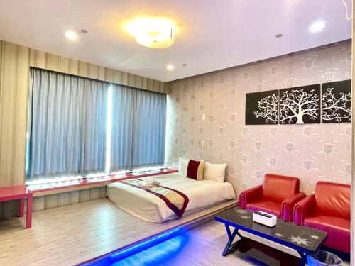 a bedroom with a bed and a couch and a window at Neo Sky Hotel in Kaohsiung