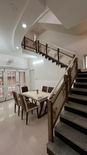a dining room with a table and a staircase at Manjul Bungalow in Nashik