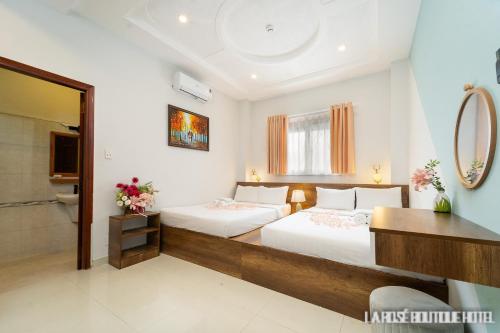 a hotel room with two beds and a mirror at La Rose Sai Gon Hotel in Ho Chi Minh City