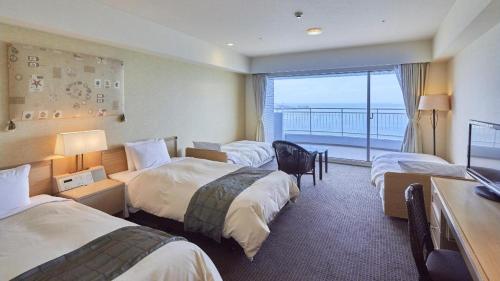 a hotel room with three beds and a balcony at Hotel Harvest Nankitanabe in Tanabe