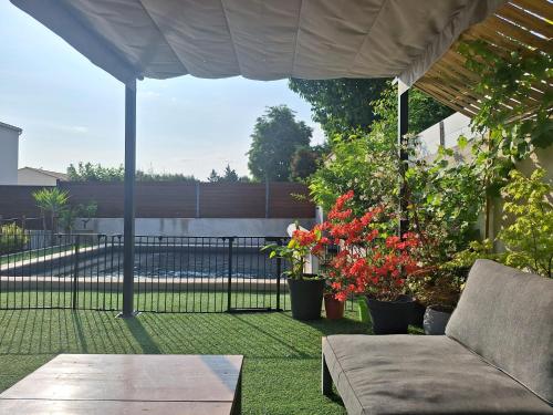 a patio with a couch and some plants and a fence at Magnifique villa à 15mn des plages in Fabrègues
