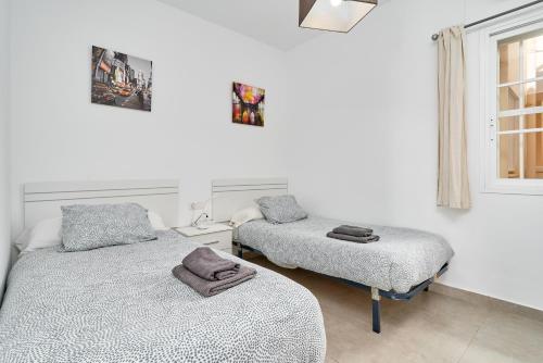 Habitación con 2 camas individuales y paredes blancas. en Apartamento Mani, en Nerja
