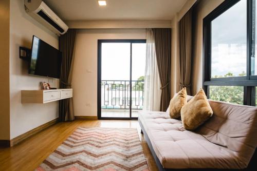 a living room with a couch and a large window at Cmor by Recall Hotels SHA Extra Plus in Chiang Mai