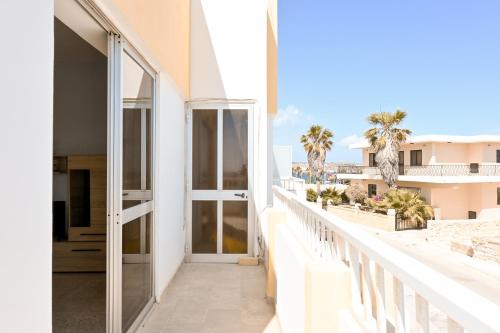 a balcony with a glass door and palm trees at Sea Blue Horizon Qawra Bay in St Paul's Bay