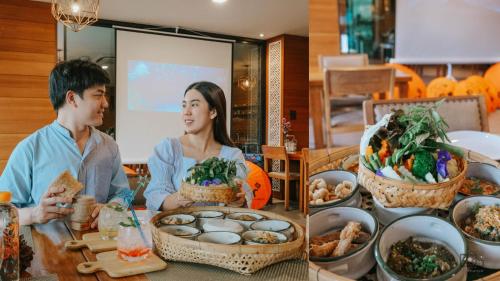 a man and a woman sitting at a table with food at Cmor by Recall Hotels SHA Extra Plus in Chiang Mai