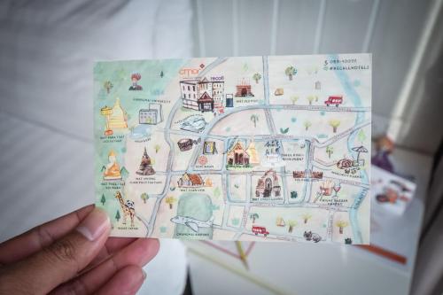 a person holding up a drawing of a map at Cmor by Recall Hotels SHA Extra Plus in Chiang Mai