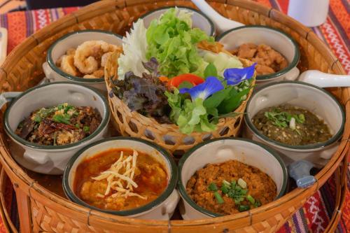 a basket full of different types of food in bowls at Cmor by Recall Hotels SHA Extra Plus in Chiang Mai