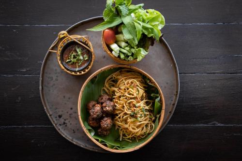 two bowls of noodles and meatballs on a table at Cmor by Recall Hotels SHA Extra Plus in Chiang Mai