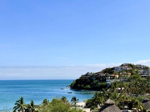 a view of a beach with palm trees and houses at Luxury Oceanview 2BR La Cruz de Huanacaxtle in Cruz de Huanacaxtle
