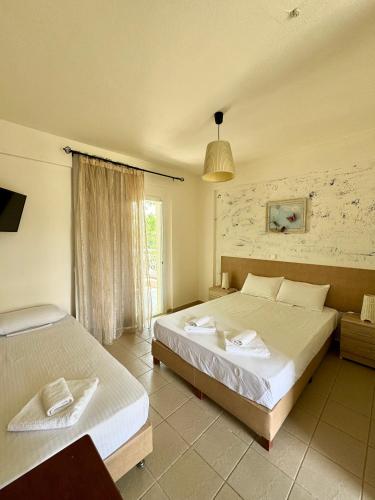ein Schlafzimmer mit zwei Betten und einem Fenster in der Unterkunft Dafnes Rooms in Fourka