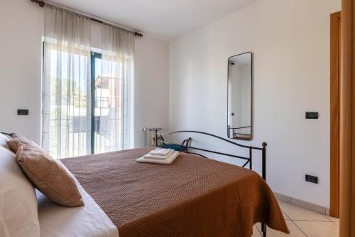 a bedroom with a bed with a mirror and a window at Little Rose garden in Aci Catena