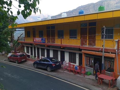 two cars parked in front of a yellow building at Kanhaiya Home Stay Guptkashi Kedarnath Road in Gupta Kāshi