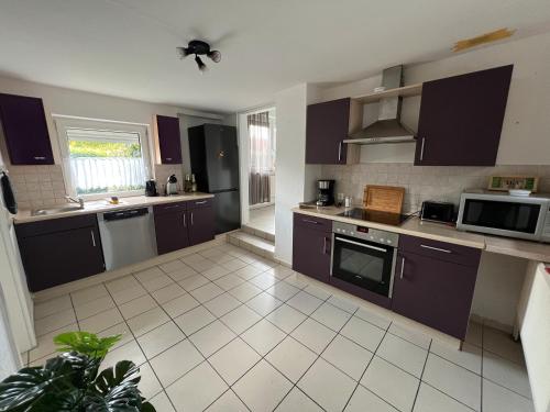 a kitchen with dark purple cabinets and appliances at Ferienhaus Almir in Haselünne