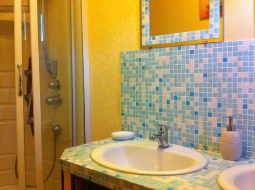 a bathroom with a sink and a blue tiled wall at Le CLOS D'ETRETAT in Les Loges