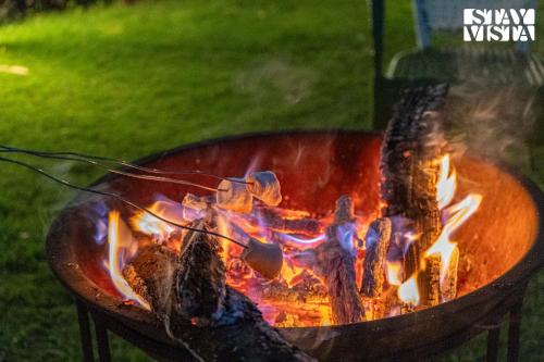 a fire pit with meat cooking in it at Corbett Calling with Projector Set-Up by StayVista in Rāmnagar
