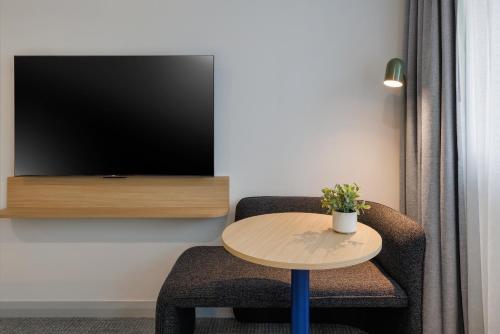 a room with a table and a chair and a tv at Quest at Sydney Olympic Park in Sydney