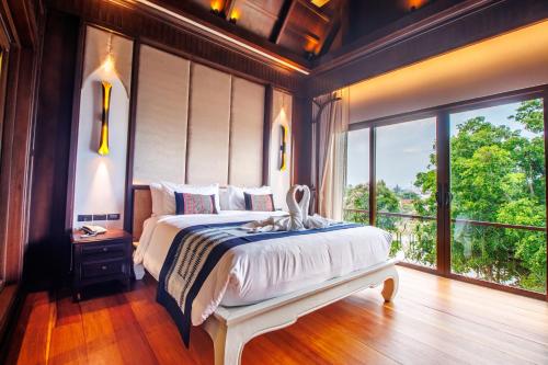a bedroom with a large bed and a large window at S48 River Ping in Chiang Mai