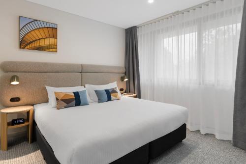 a hotel room with a large bed and a window at Quest at Sydney Olympic Park in Sydney