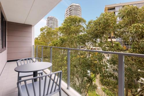 a balcony with a table and chairs and tall buildings at Quest at Sydney Olympic Park in Sydney