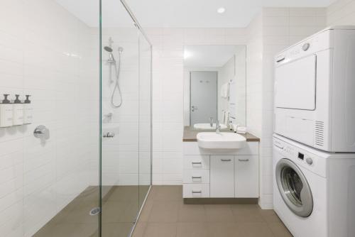 a bathroom with a sink and a washing machine at Quest at Sydney Olympic Park in Sydney