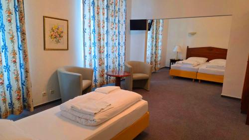 a hotel room with two beds and a table and chairs at Eifeler Hof - Ihr Restaurant für Genussmomente in Kyllburg in Kyllburg