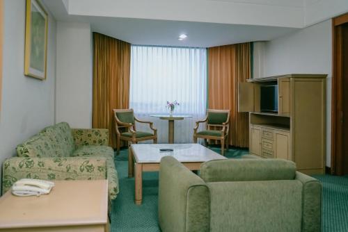 a living room with two couches and a table and a television at Horison Ultima Bandung in Bandung