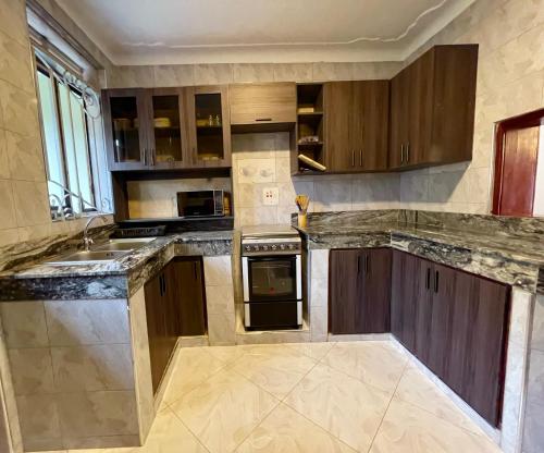 a large kitchen with wooden cabinets and a sink at Efrona Homes in Kampala