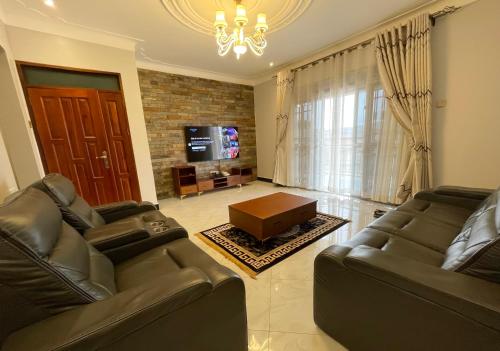 a living room with two leather couches and a tv at Efrona Homes in Kampala